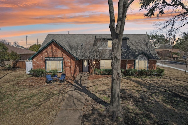 view of front of property with brick siding and roof with shingles