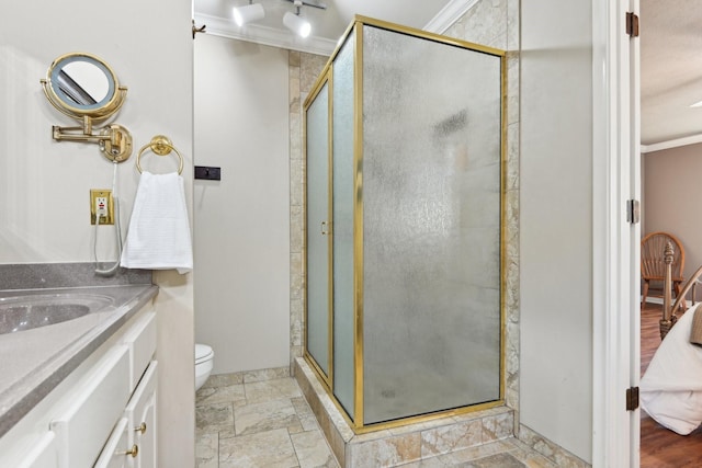 bathroom with a stall shower, toilet, ornamental molding, stone finish flooring, and vanity