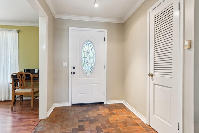 foyer with ornamental molding, brick floor, and baseboards