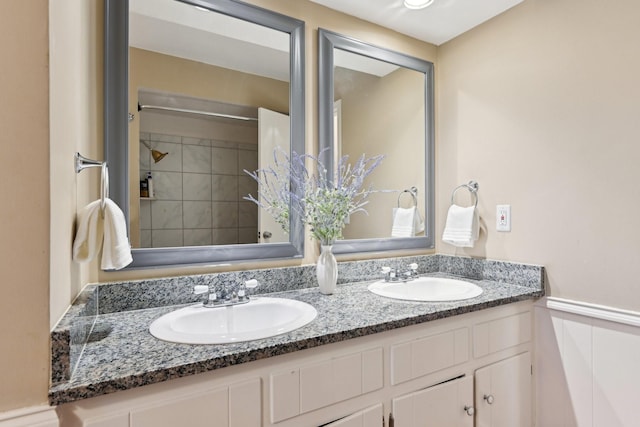 full bath featuring double vanity, a sink, and wainscoting