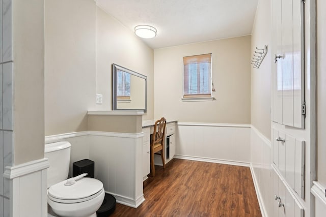 bathroom with toilet, wood finished floors, and wainscoting