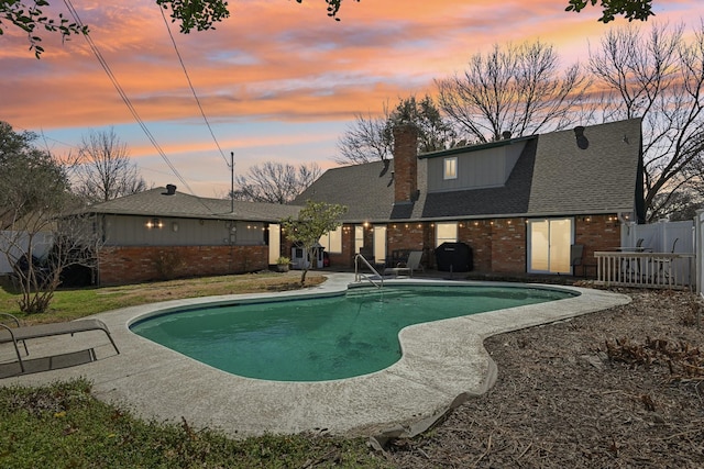 outdoor pool with area for grilling, a patio area, and fence