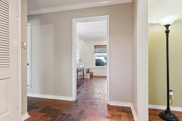 hallway with ornamental molding, brick floor, and baseboards