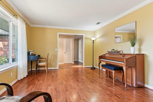 sitting room featuring baseboards, visible vents, wood finished floors, and ornamental molding