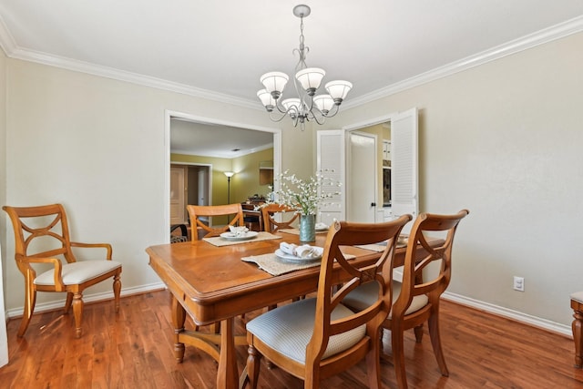 dining space featuring crown molding, a notable chandelier, baseboards, and wood finished floors