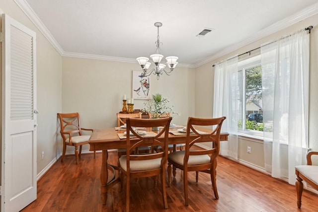 dining area featuring an inviting chandelier, crown molding, visible vents, and wood finished floors