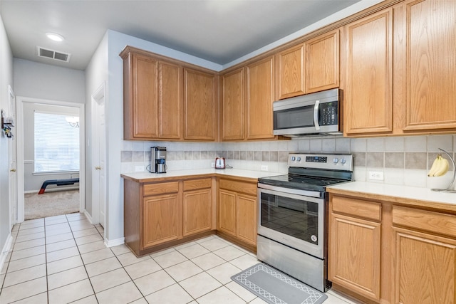 kitchen featuring backsplash, visible vents, stainless steel appliances, and light countertops