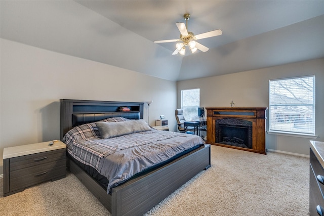 bedroom featuring ceiling fan, light colored carpet, a fireplace, baseboards, and vaulted ceiling