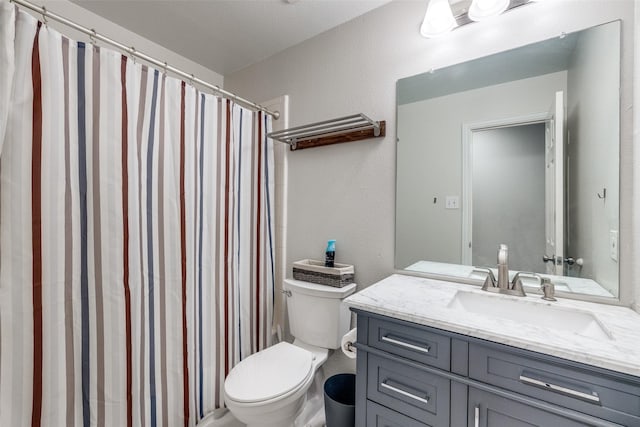 full bath featuring toilet, curtained shower, a textured wall, and vanity