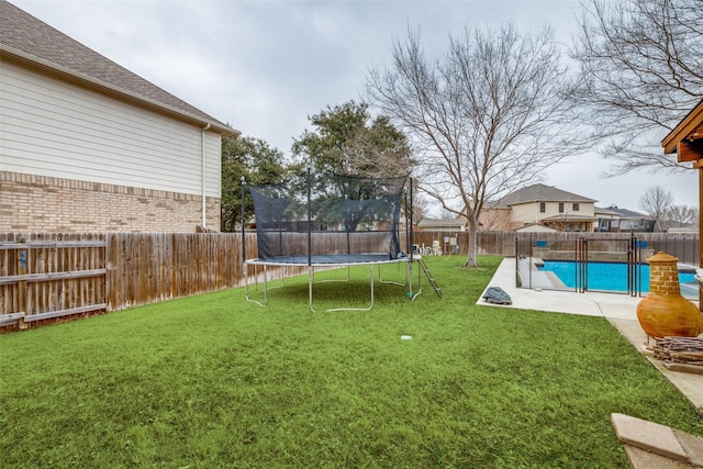 view of yard featuring a fenced in pool, a fenced backyard, and a trampoline