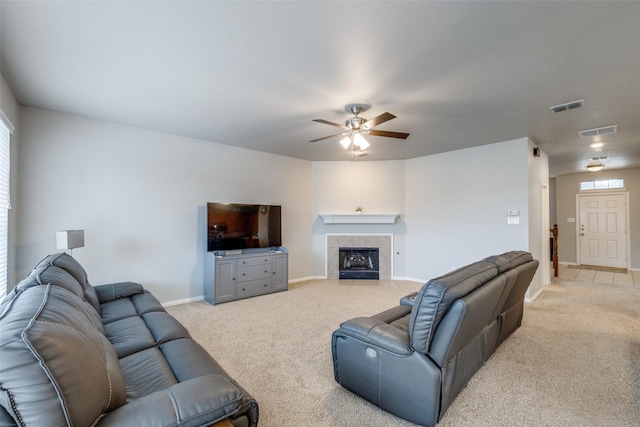 living area featuring visible vents, light carpet, and a tiled fireplace