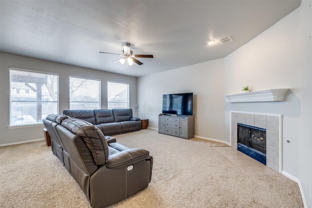 living room with plenty of natural light, visible vents, carpet flooring, and a tile fireplace