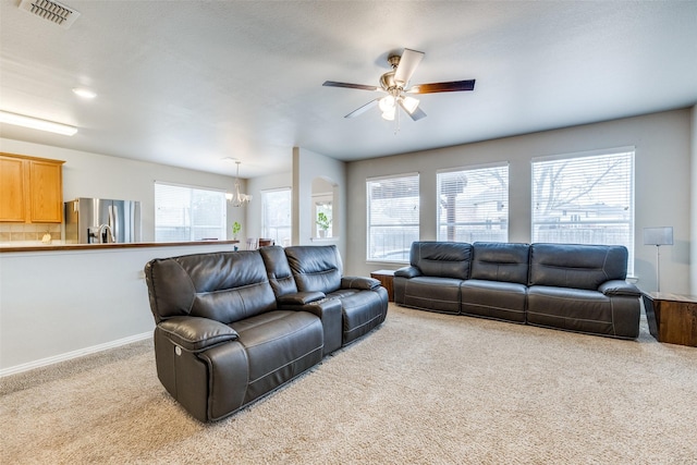 living room featuring carpet floors, visible vents, baseboards, and ceiling fan with notable chandelier