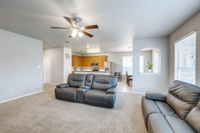 living room featuring light carpet, ceiling fan, visible vents, and baseboards