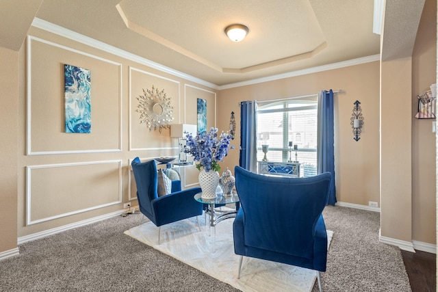 living area with a decorative wall, carpet flooring, baseboards, ornamental molding, and a tray ceiling