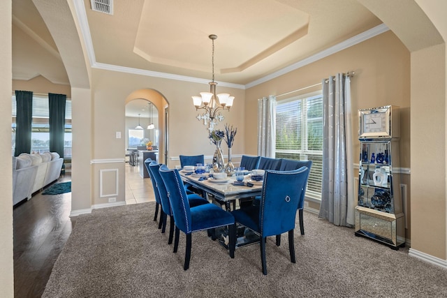 dining room with visible vents, arched walkways, a raised ceiling, and a notable chandelier