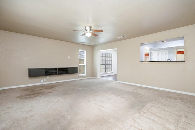 unfurnished living room with baseboards, carpet floors, visible vents, and a ceiling fan