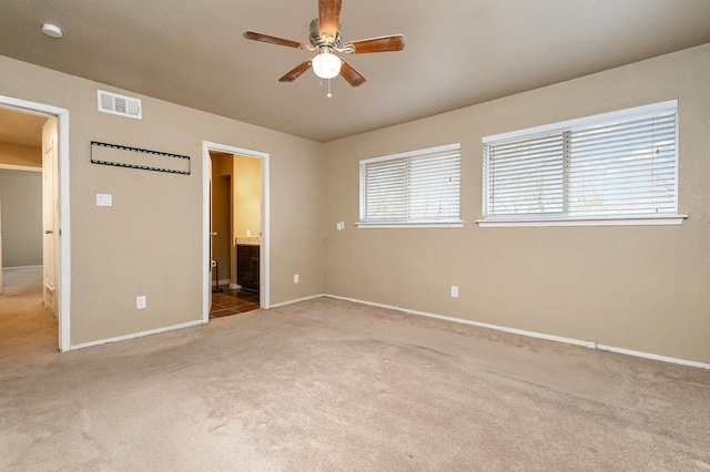 unfurnished bedroom featuring ensuite bath, carpet, visible vents, and baseboards