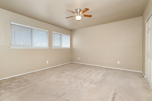 carpeted empty room featuring a ceiling fan and baseboards