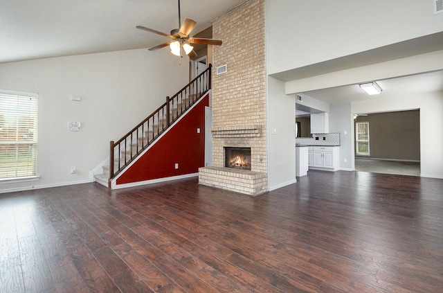 unfurnished living room with a fireplace, stairway, ceiling fan, wood finished floors, and baseboards