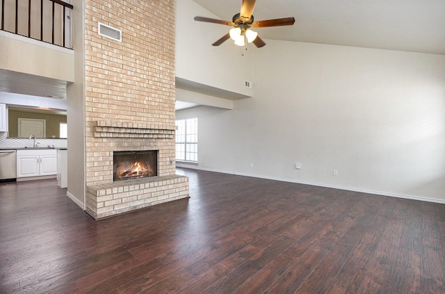 unfurnished living room featuring dark wood finished floors, visible vents, a brick fireplace, ceiling fan, and baseboards