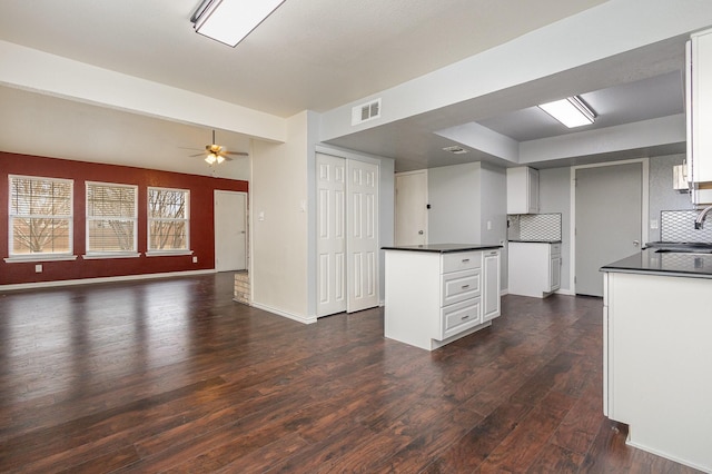 kitchen with dark countertops, dark wood-style flooring, visible vents, and a sink