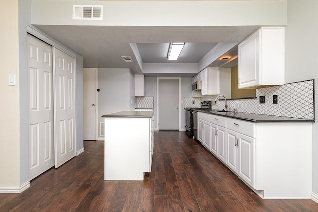 kitchen with stainless steel appliances, dark countertops, visible vents, and a sink