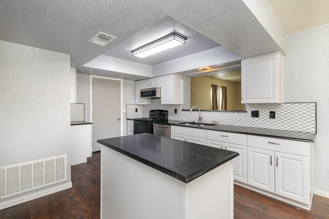 kitchen with appliances with stainless steel finishes, dark countertops, visible vents, and a sink