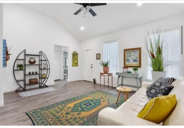 living area featuring high vaulted ceiling, ceiling fan, baseboards, and wood finished floors