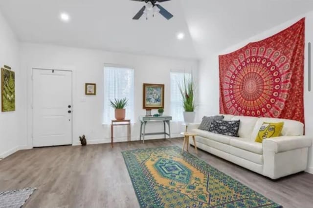 living area featuring ceiling fan, baseboards, vaulted ceiling, and wood finished floors