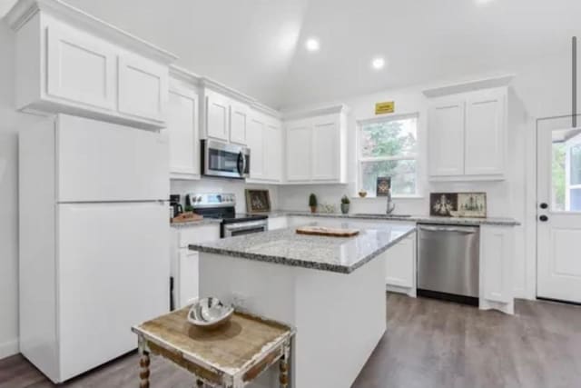 kitchen featuring appliances with stainless steel finishes, a wealth of natural light, white cabinetry, and a kitchen island