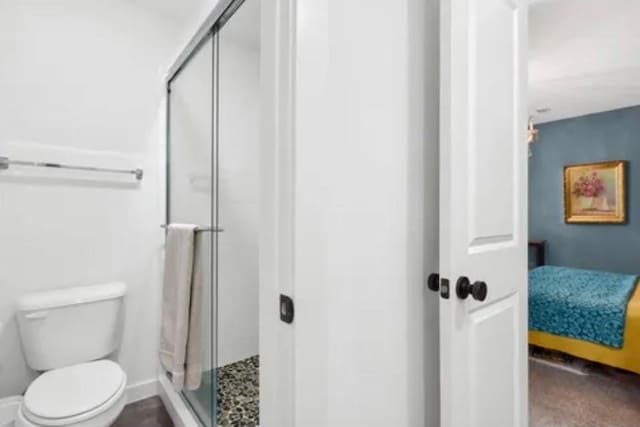 ensuite bathroom with baseboards, a shower stall, toilet, and connected bathroom