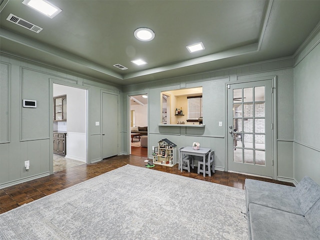 interior space featuring visible vents, a raised ceiling, and a decorative wall