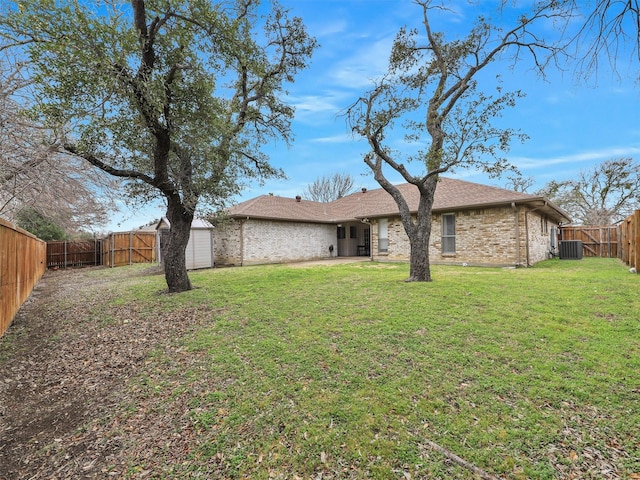 back of house with brick siding, a lawn, central AC unit, a fenced backyard, and an outdoor structure