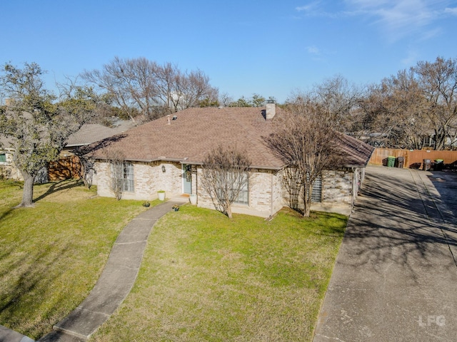 view of front of home featuring brick siding, roof with shingles, fence, and a front yard