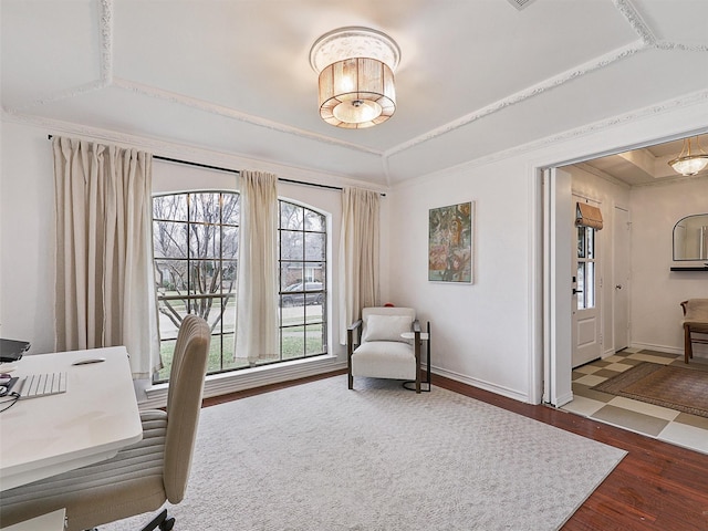 office area with ornamental molding, a tray ceiling, baseboards, and wood finished floors