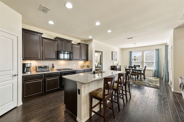 kitchen with a sink, dark wood-type flooring, black microwave, and stainless steel gas stovetop