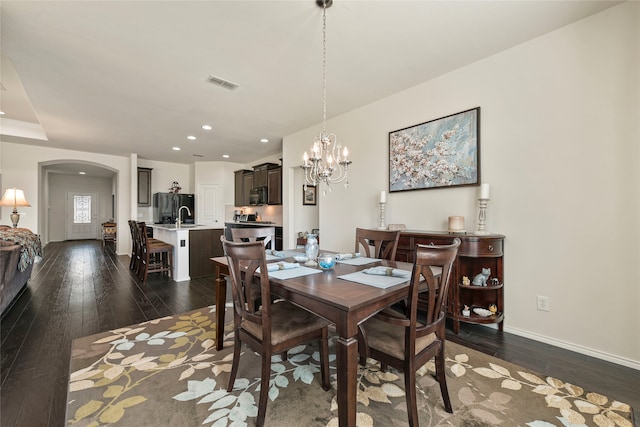 dining space with dark wood-style floors, recessed lighting, visible vents, and arched walkways