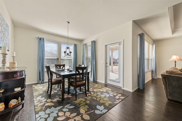 dining space featuring dark wood finished floors, a notable chandelier, and baseboards