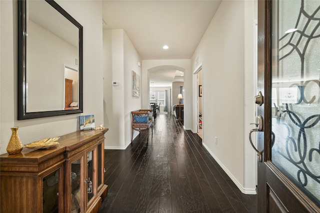 hallway with arched walkways, dark wood-style floors, recessed lighting, and baseboards