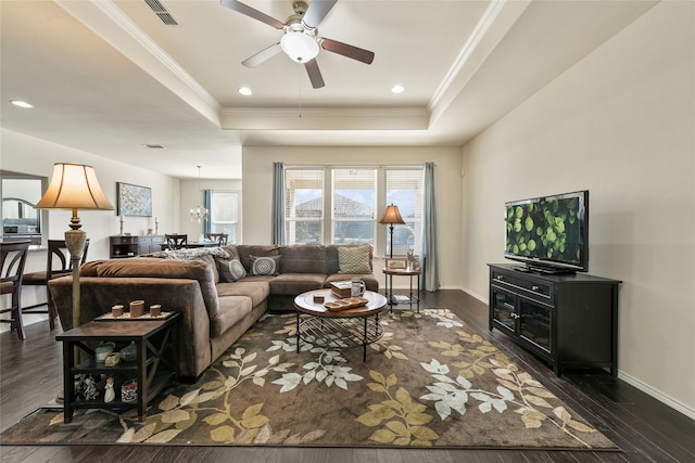 living room featuring visible vents, a raised ceiling, dark wood finished floors, and ornamental molding