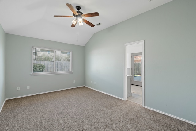 unfurnished room featuring carpet flooring, visible vents, a ceiling fan, vaulted ceiling, and baseboards