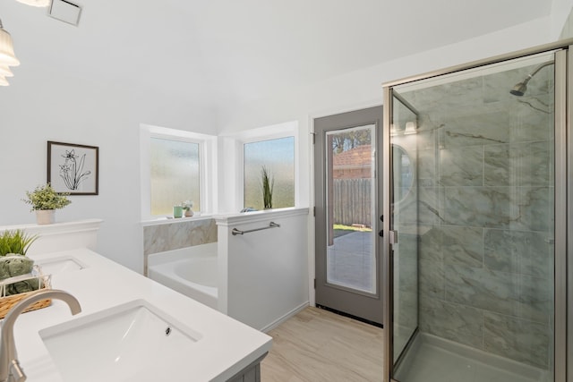 full bathroom featuring double vanity, a stall shower, a garden tub, and a sink