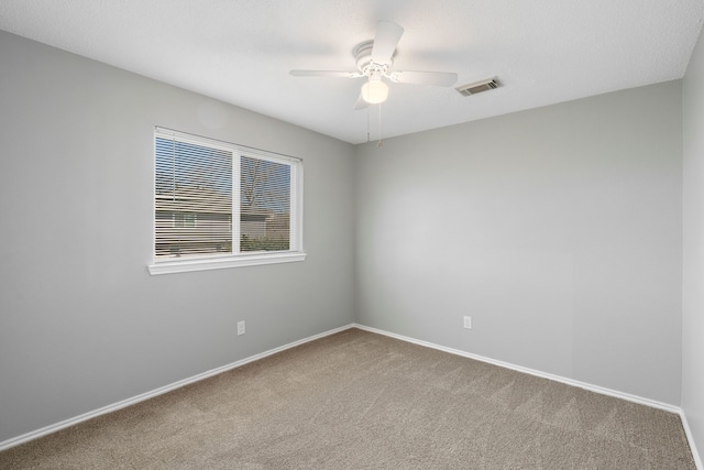 carpeted empty room with ceiling fan, visible vents, and baseboards