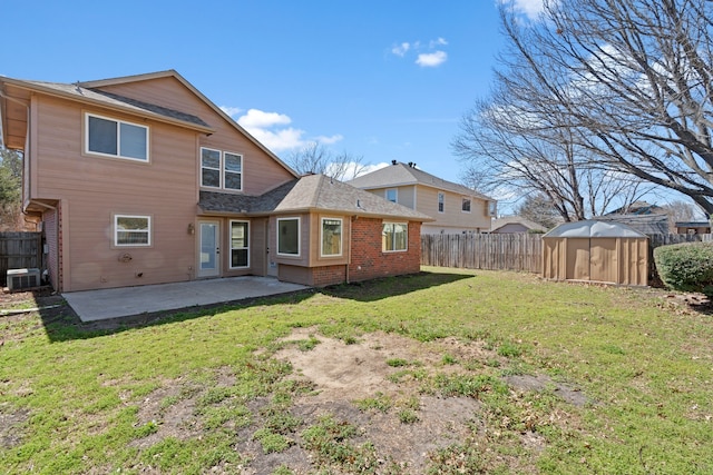 rear view of house with an outbuilding, a fenced backyard, brick siding, a yard, and a patio area