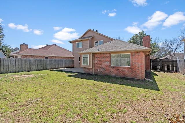 rear view of property featuring a lawn, a fenced backyard, a chimney, roof with shingles, and brick siding