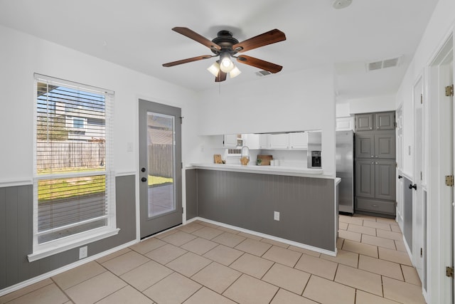 kitchen featuring gray cabinetry, a peninsula, visible vents, light countertops, and stainless steel fridge with ice dispenser