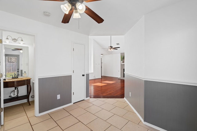 spare room featuring a wainscoted wall, ceiling fan, light tile patterned floors, and lofted ceiling