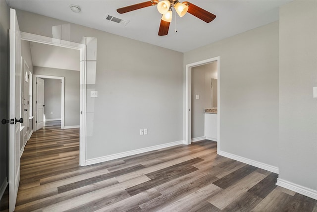 spare room with a ceiling fan, wood finished floors, visible vents, and baseboards