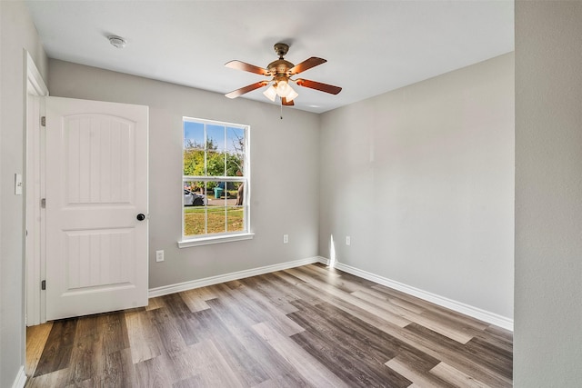 unfurnished room with wood finished floors, a ceiling fan, and baseboards